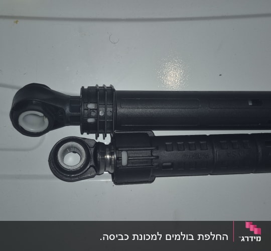 שני בולמי זעזועים שחורים מונחים על משטח לבן